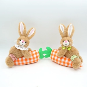 Detailed view of two plush Easter bunnies with lace bowties holding a large fabric carrot