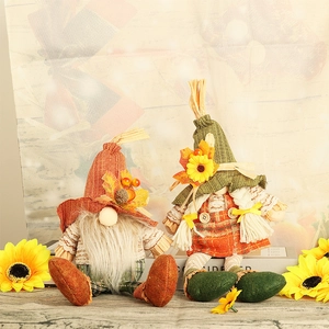 Close-up of autumn gnome dolls featuring orange maple leaf hat and green sunflower knits
