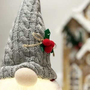 Macro detail of a lighted Christmas gnome showing knit hat texture and warm LED glowing beard