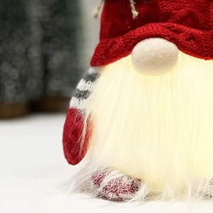 Detail of a Christmas gnome with glowing LED beard and a red knitted hat with warm lights