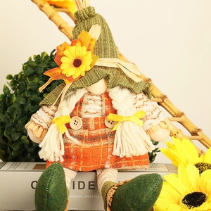 Close-up of autumn gnome doll with green knitted hat, sunflower, and orange plaid dress