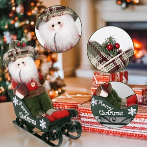 Plush Santa doll in red suit sitting on a green metal sleigh with Merry Christmas script