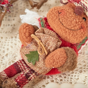 Detail of plush Christmas reindeer ornament with red knit hat and small burlap gift bag