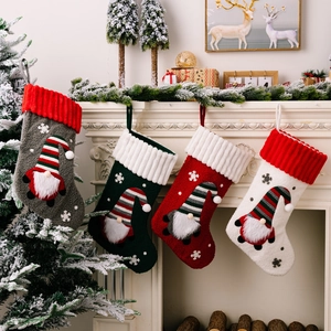 Set di quattro calze di Natale in peluche con gnomi 3D appesi a un camino bianco