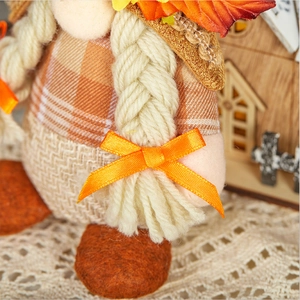 Close-up of braided yarn pigtails with orange bows on a fall harvest gnome decoration