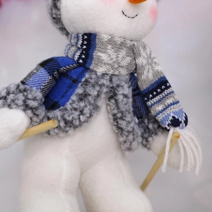 Detailed close-up of a plush snowman in blue plaid jacket with cozy knitted scarf