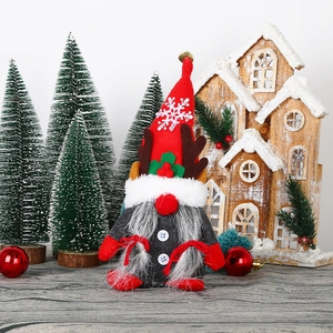 Christmas gnome doll with reindeer antlers and red hat standing in a festive winter scene