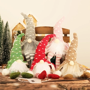 Set of five glowing Christmas gnomes with knitted hats and striped legs on wooden background
