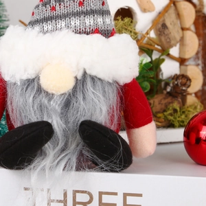 Christmas plush gnome ornament with grey knitted hat and red felt suit on pine needles