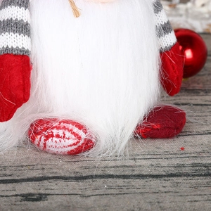 Detail of Christmas gnome showing long white faux fur beard and striped knit sleeves