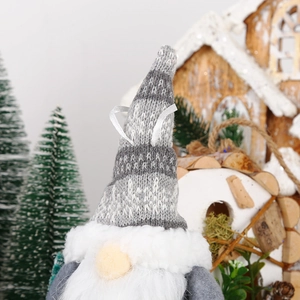 Detail of knitted gnome ornament with striped hat on a festive Christmas tree background
