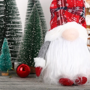 Close-up of a Christmas gnome with red plaid hat next to miniature holiday trees