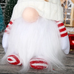 Close-up of a Christmas gnome with white knitted hat and faux fur beard on festive wood background