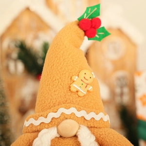 Détail du chapeau de gnome en peluche avec motif pain d'épices et baies de houx