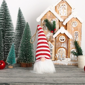Knitted Christmas gnome ornament with striped hat and white beard hanging on tree