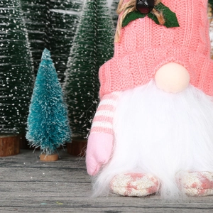 Detail of pink knitted Christmas gnome with holly leaves and plush white beard decor