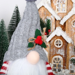 Close-up of a Christmas gnome with gray knit hat and red berries in a festive decor