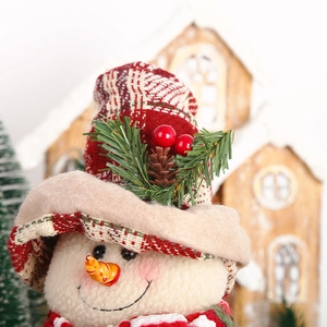 Close-up of plush snowman doll head with plaid hat and festive pine cone details