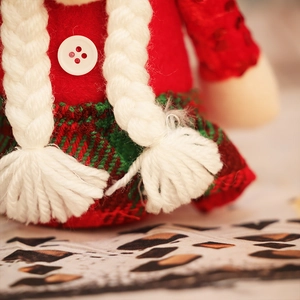 Detailed close-up of knit braids and red felt Christmas gnome with tartan skirt