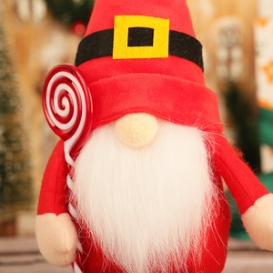 Close-up of a red Christmas gnome with long white beard holding a striped lollipop