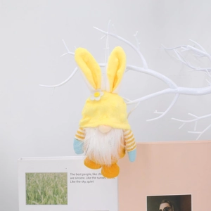 Gnomo pasquale di peluche con orecchie di coniglio gialle appeso a un ramo decorativo