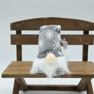 Close-up of a Christmas gnome with snowflake knit hat sitting on a small wooden bench