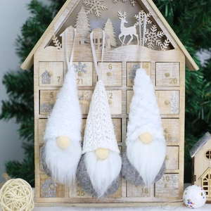 Detailed view of three handmade knitted gnome ornaments hanging on a festive wooden house