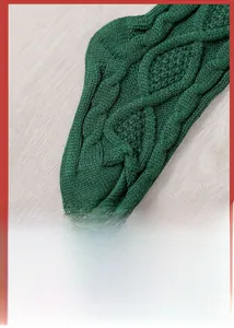 Detail of dark green knitted Christmas stocking with classic cable knit pattern on wood