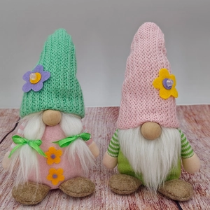 Macro detail of gnome plush with green knit floral hat and white braided pigtails