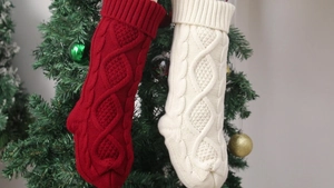 Detail of red and cream cable knit Christmas stockings hanging on a festive decorated tree