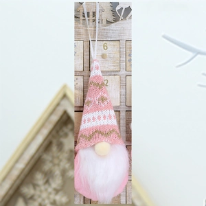Detail of pink knitted Christmas gnome ornament with snowflake pattern and long white beard