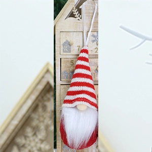 Close-up of a red and white knitted Christmas gnome ornament with a hanging string and soft beard