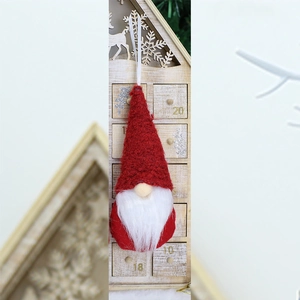 Detail of red Christmas gnome ornament with white beard and knitted hat hanging on wood