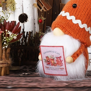 Knitted Christmas Gnome doll with orange hat holding a Gingerbread Cafe sign decoration
