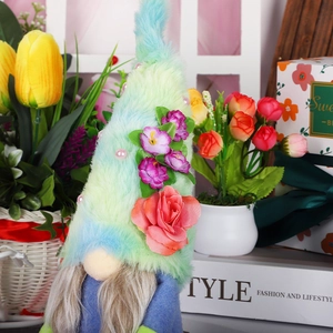 Makroaufnahme von Plüsch-Gnom mit blauem Hut, Rosen und Blumen für die Wohndeko