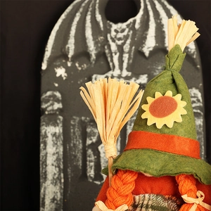 Detail of harvest gnome doll with sunflower hat, orange braids, and mini straw broom