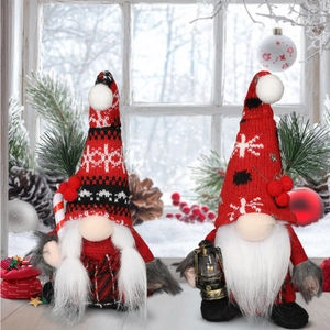 Close-up of Christmas gnomes with knitted hats and holiday props on a snowy window