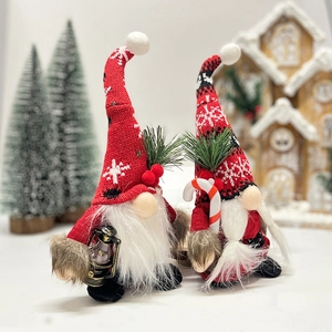 Pair of Christmas gnomes with knit snowflake hats holding a lantern and candy cane décor