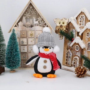 Close-up of penguin gnome toy with gray knit hat and red snowflake scarf in a festive set