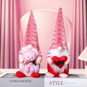 Pink and red Valentine's gnomes holding a heart and plush bear on a decorative book stack