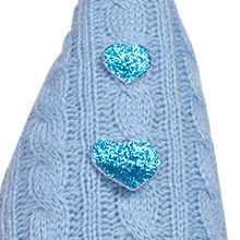 Detail of light blue cable knit fabric with glittering heart patches on the gnome doll
