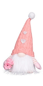 Close-up of pink gnome with knitted hat, silver hearts and artificial rose flowers