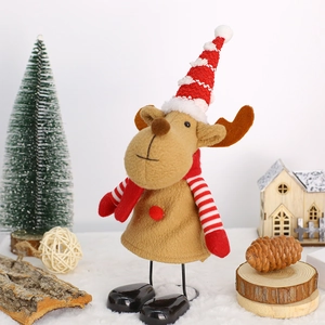 Detail of a plush Christmas reindeer decoration with striped hat on a snowy winter background