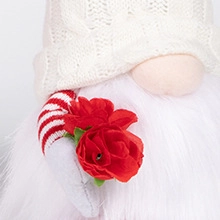 Détail d'un gnome en peluche tenant des roses en tissu rouge avec fausse fourrure blanche