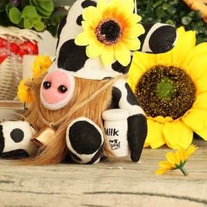 Detailed view of a cow-themed gnome doll with sunflower hat holding a milk bottle prop