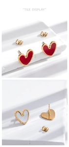 Macro shot of heart-shaped gold-rimmed earrings with red and white enamel detailing