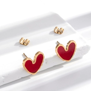 Elegant red heart stud earrings with gold trim on minimalist white marble stand