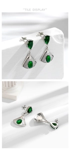 Macro view of fan-shaped steel earrings with teardrop green zircon and silver finish