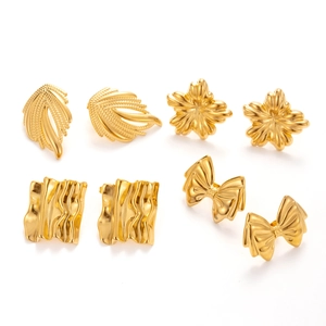 Set di orecchini in acciaio dorato con forme di fiocco e fiori su sfondo bianco