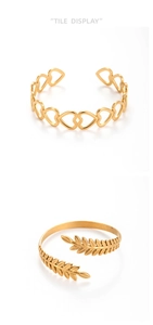 Dettaglio di due bracciali rigidi dorati con motivi a cuore e foglie traforate